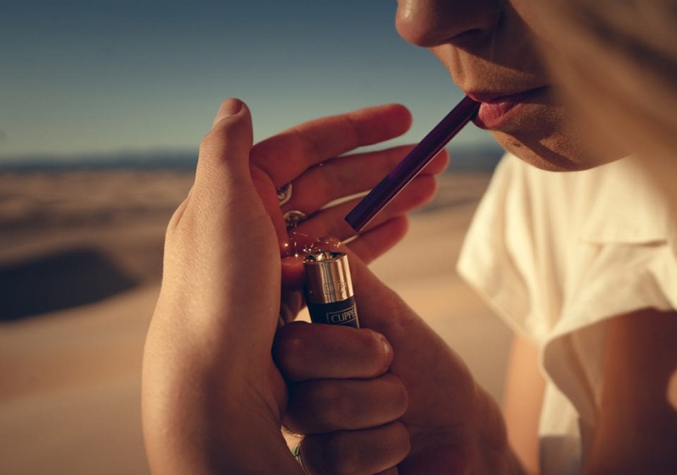 Person using The Dart one-hitter in a desert landscape